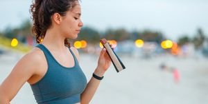 young woman on a break from jogging, eating protein bar