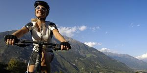 Young woman on a mountain bike under blue sky, Val Venosta, South Tyrol, Italy, Europe
