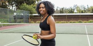 a young black woman on a tennis court holding a racket and bal