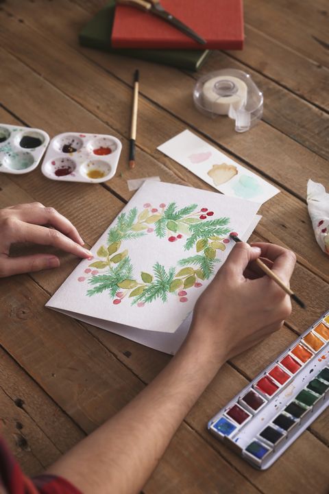 young woman painting christmas card with water colors, close up