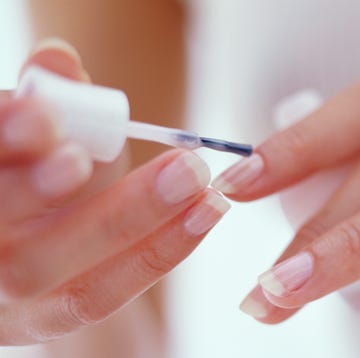 young woman painting fingernails, close up