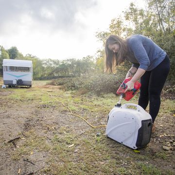 young woman pouring gas into the generator at camp
