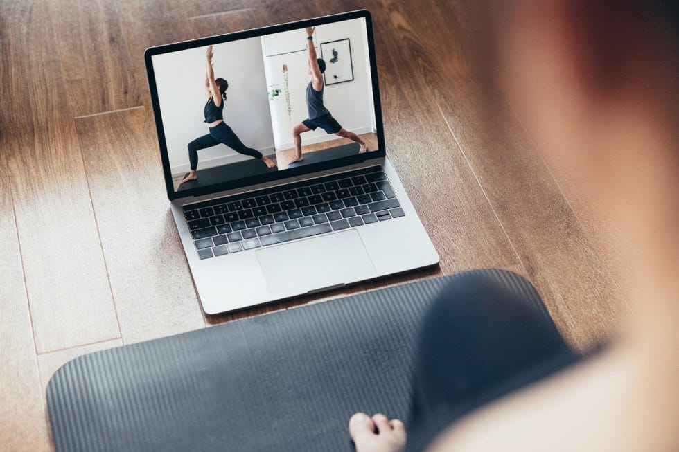 young woman practising yoga workout with a video lesson on laptop