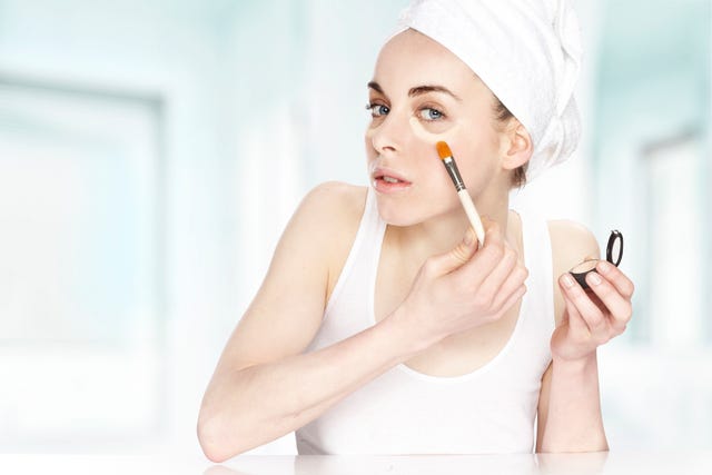 una chica joven se pone, con pincel, un producto para corregir las ojeras