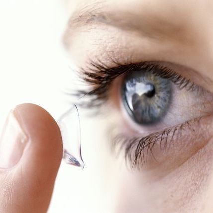 YOUNG WOMAN PUTTING CONTACT LENS IN EYE