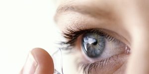 YOUNG WOMAN PUTTING CONTACT LENS IN EYE