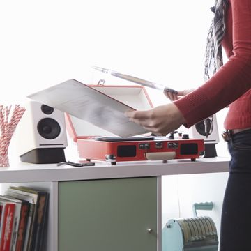 Young woman putting vinyl on record player at christmas