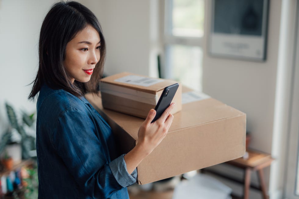 woman holding two boxes and looking at phone, giving up online shopping for lent