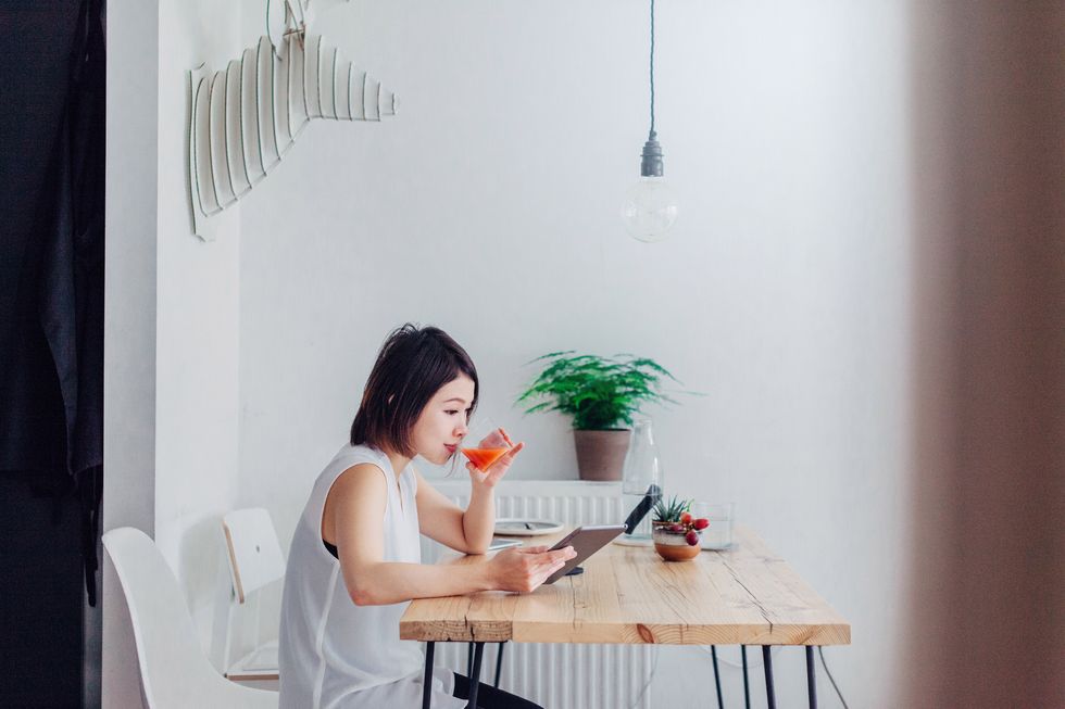young woman reading news on tablet whilst having breakfast