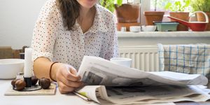 young woman reading newspaper in kitchen