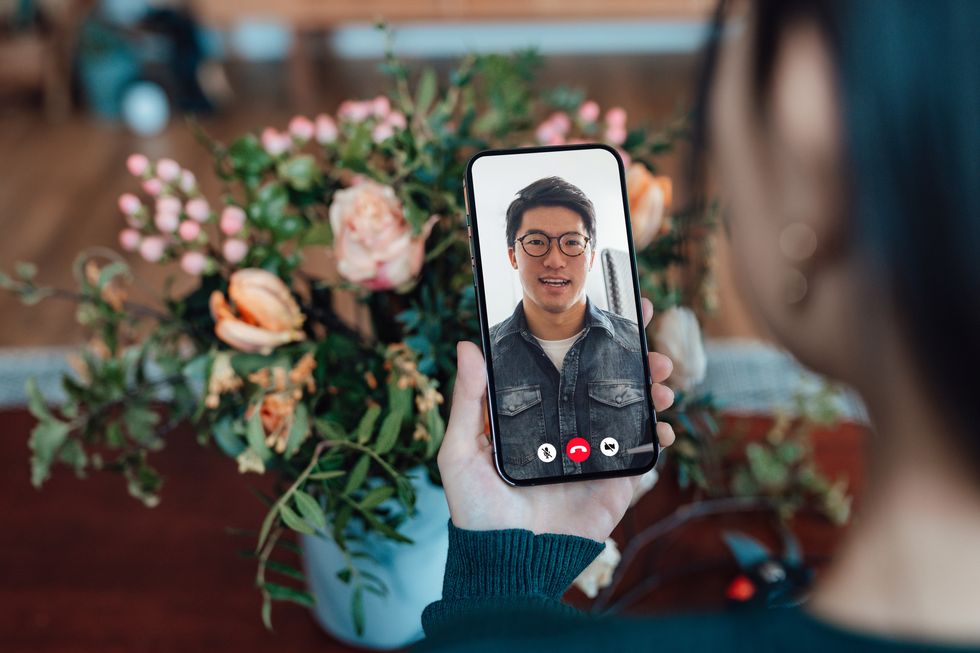 young woman receiving flower bouquet while having a video call with her love