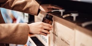 young woman refilling shower gel into a reusable glass bottle in zero waste store