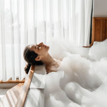 young woman relaxing in bath tub full of foam bubbles self care and mental health concept