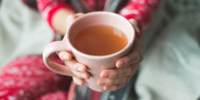 Young woman relaxing in bed with a cup of tea