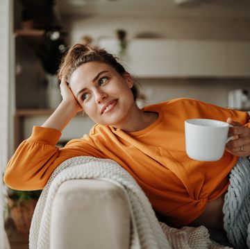 young woman resting on sofa with cup of tea