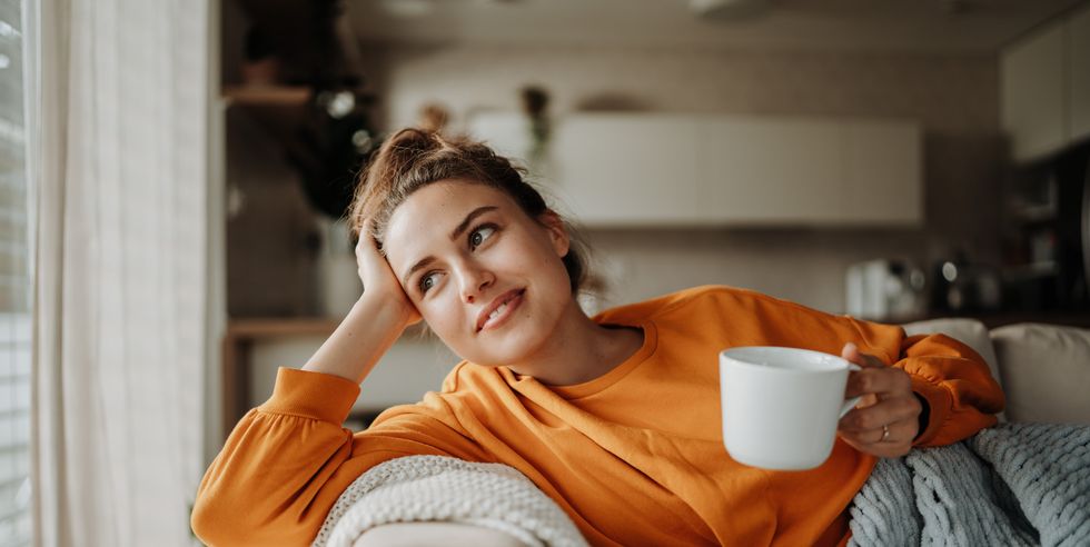 young woman resting on sofa with cup of tea