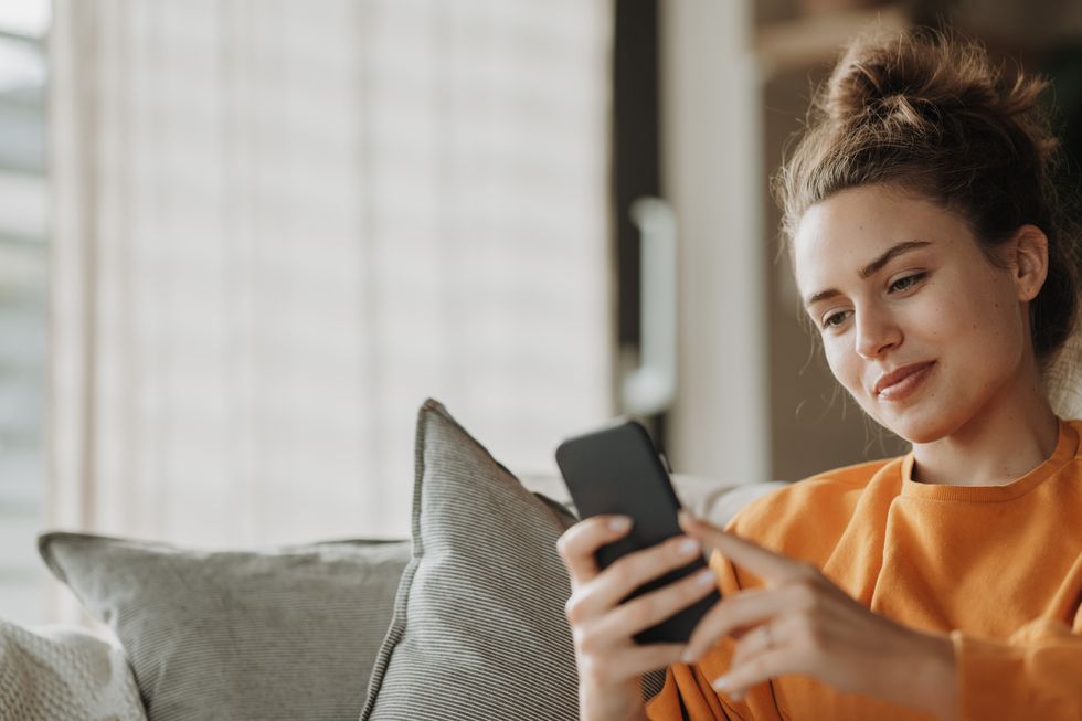 young woman resting on sofa with smartphone