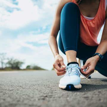 woman bends down to tie sneaker