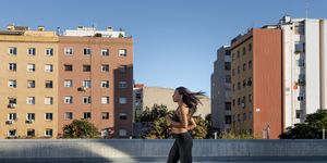 Young woman running along apartment blocks in the city