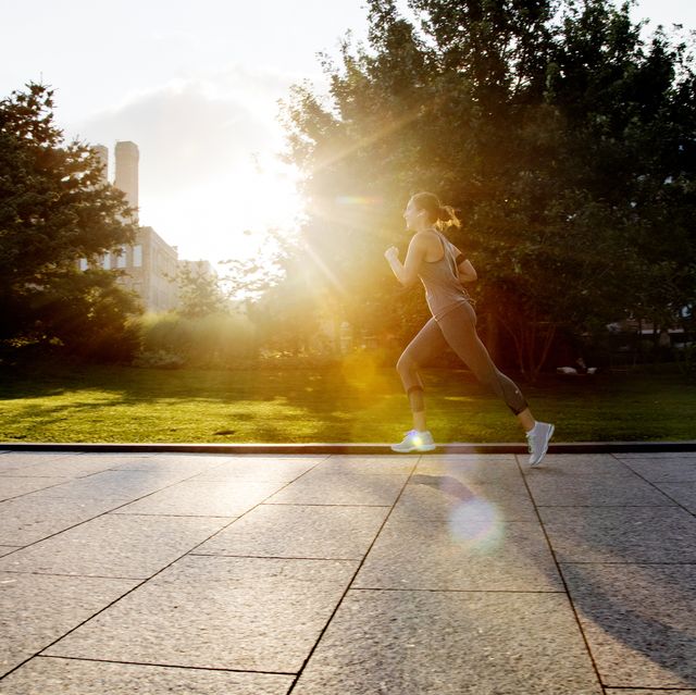young woman running in park with morning sunlight