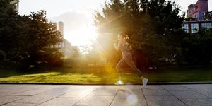 young woman running in park with morning sunlight