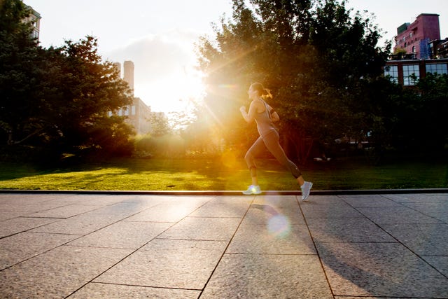 young woman running in park with morning sunlight