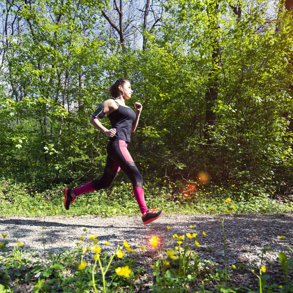 a young woman running in the forest footpath.