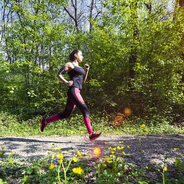 a young woman running in the forest footpath.