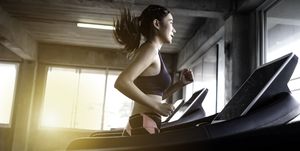 young woman running on treadmill at gym