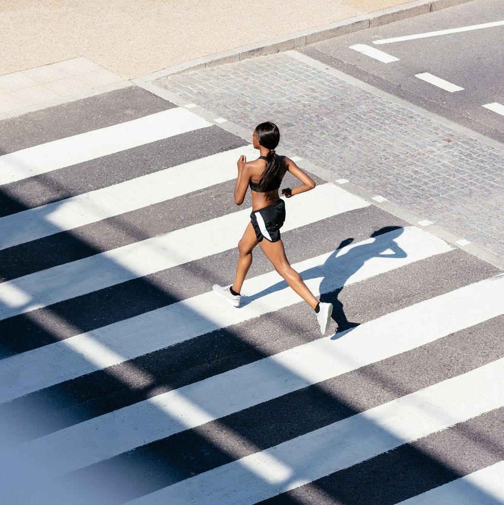 young woman running on zebra crossing