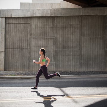 young woman running under freeway overpass