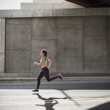 young woman running under freeway overpass