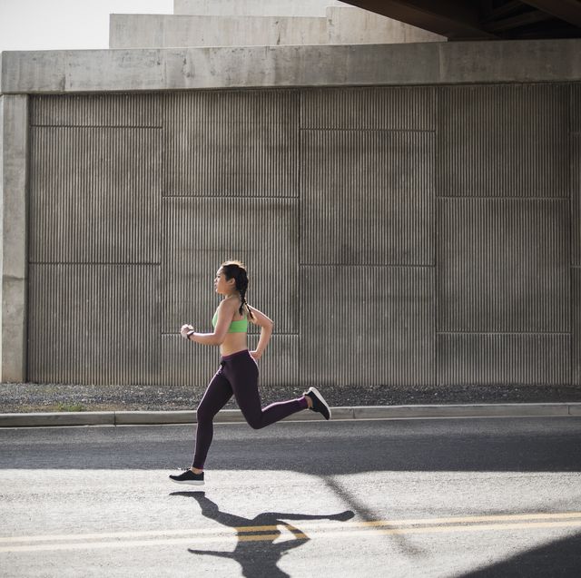 young woman running under freeway overpass
