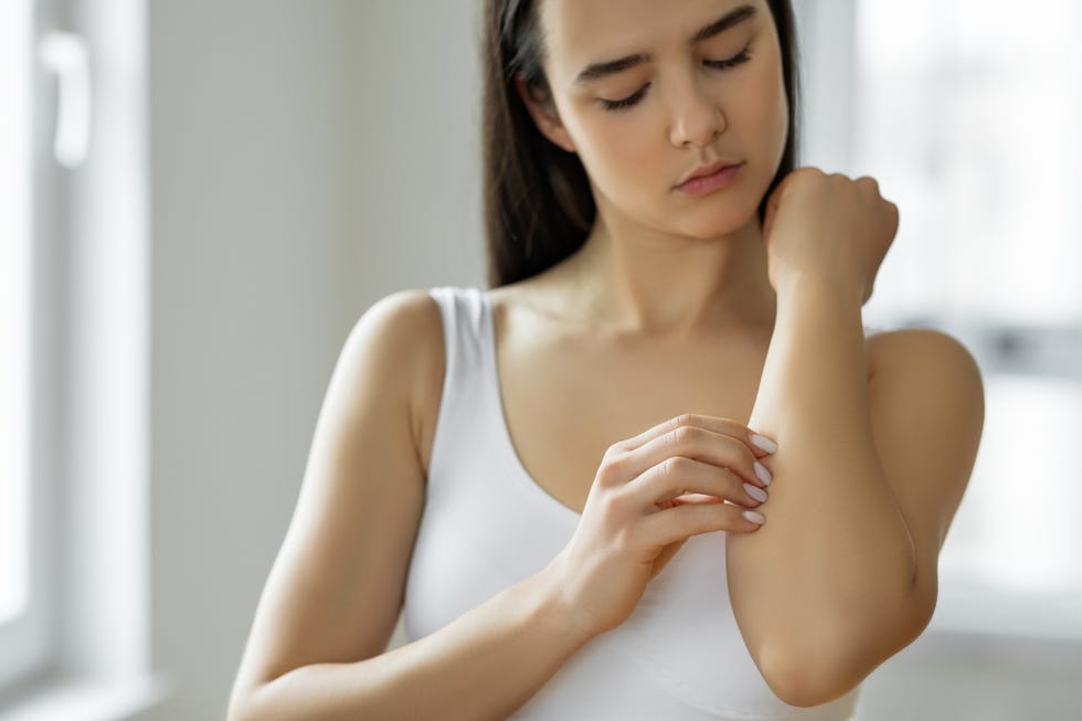 young woman scratching her arm