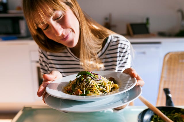 young woman serving vegan pasta dish