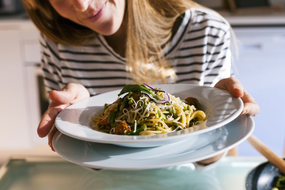 young woman serving vegan pasta dish