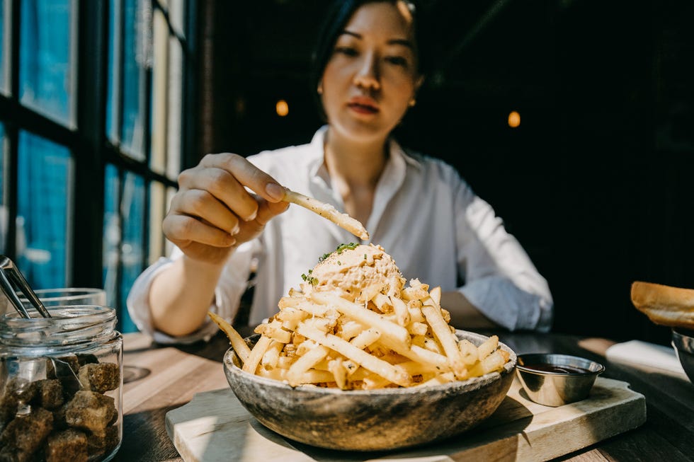 healthy dining out - Young woman sitting by the window in restaurant enjoying french fries and meal