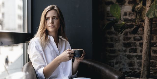 Young woman sitting in cafe, drinking coffee