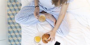 young woman sitting on bed and having a coffee