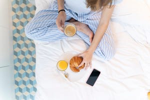 young woman sitting on bed and having a coffee