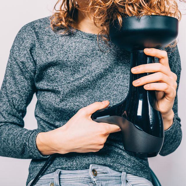 young woman sitting on chair holding hairdryer