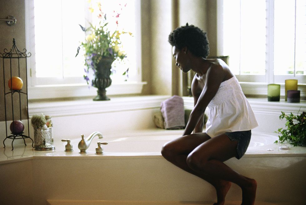 young woman sitting on edge of bathtub