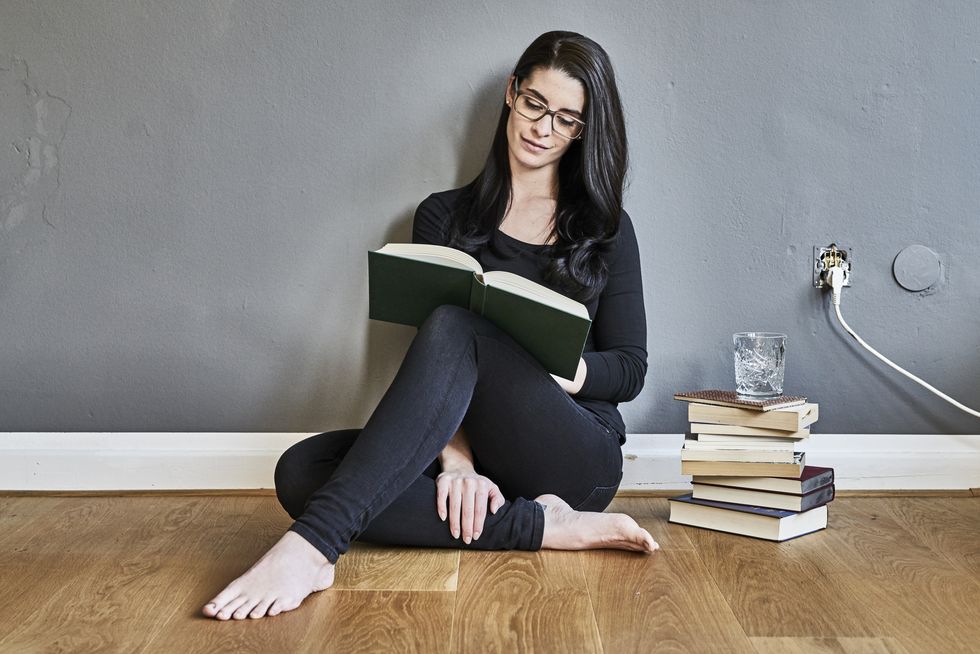 Young woman sitting on the floor reading book