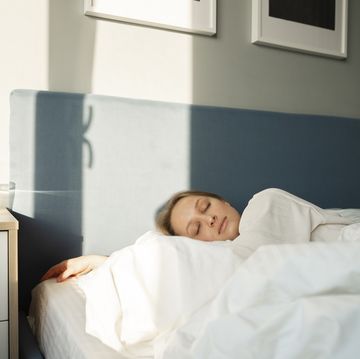young woman sleeping in bed by table at home