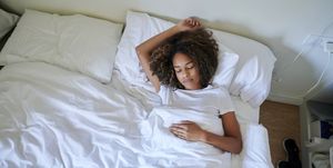young woman sleeping on bed in bedroom at home