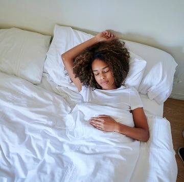 young woman sleeping on bed in bedroom at home