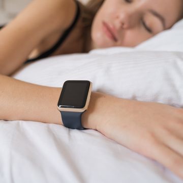 woman sleeping on bed with smart watch tracking sleep