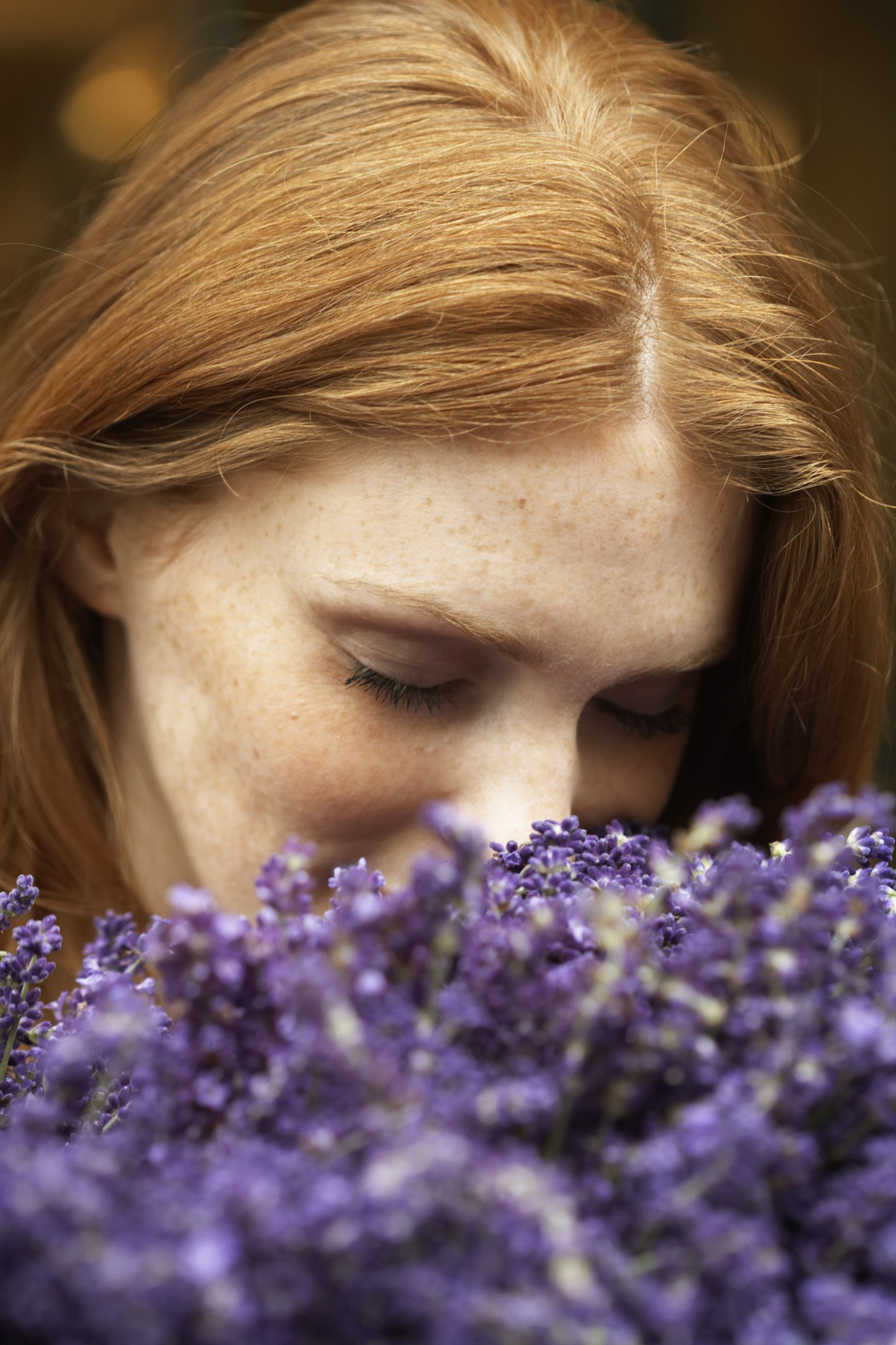 young woman smelling lavendar, eyes closed, close up