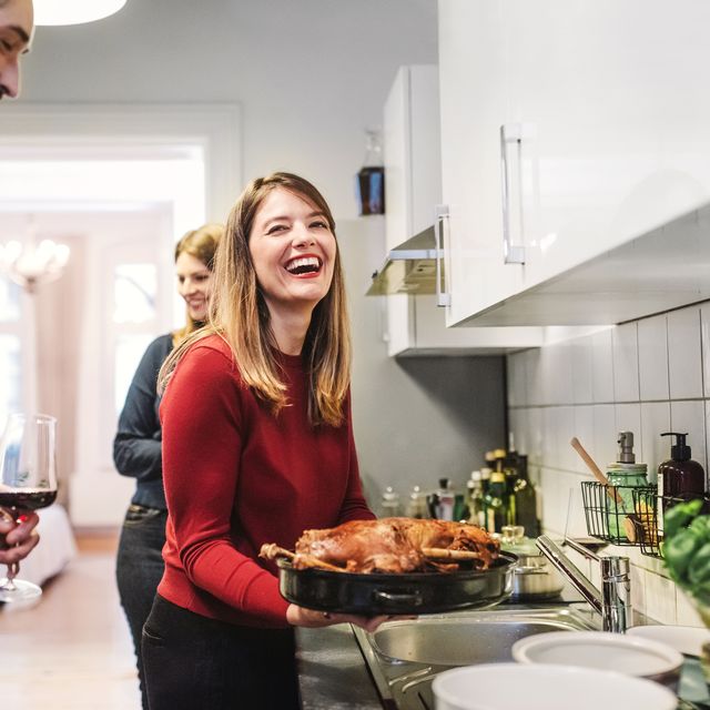 young woman smiling and holding christmas poultry in kitchen