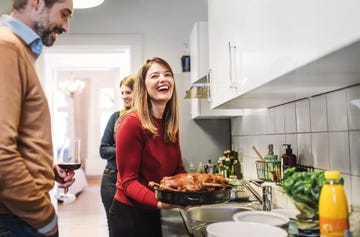 young woman smiling and holding christmas poultry in kitchen